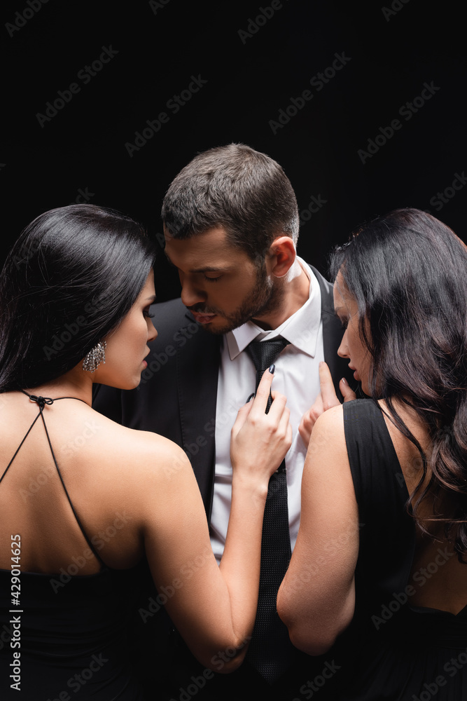 elegant, brunette women near young man in suit isolated on black.