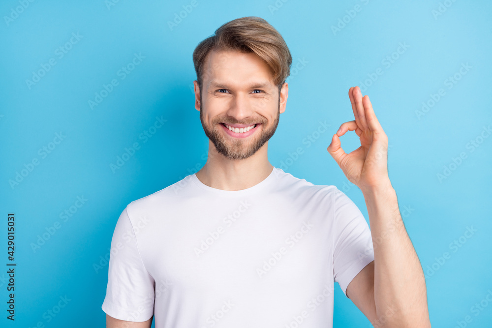 Photo portrait of handsome man wearing white t-shirt showing okay gesture smiling isolated bright blue color background Photo portrait of handsome man wearing white t-shirt showing okay gesture smiling isolated bright blue color background