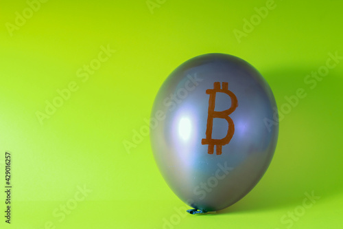 Balloon depicting gray bitcoin on a green background. The concept of rapid decline of cryptocurrency.