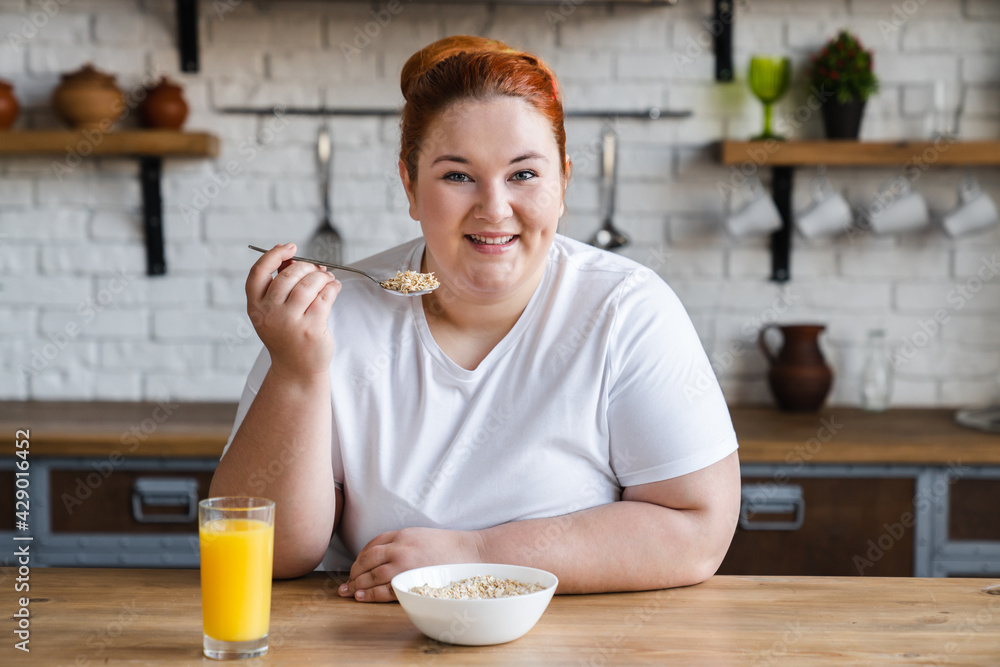 Happy caucasian fat obese plump woman eating flakes for healthy eating habits. Overweight woman dieting for being in sporty shape. Happy caucasian fat obese plump woman eating flakes for healthy eating habits. Overweight woman dieting for being in sporty shape.