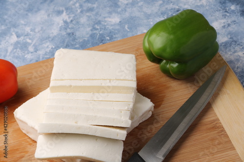 Paneer or cottage cheese with tomatoes, capsicum  and a knife on a wooden cutting Board. photo