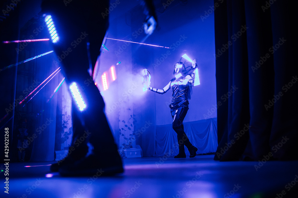 Obraz premium digital art dance show in LED costumes. neon fans in the hands of artists dancing in the dark on stage