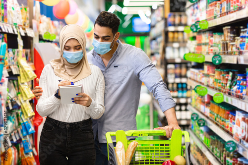 Muslim Family Doing Grocery Shopping In Supermarket, Wearing Face Masks