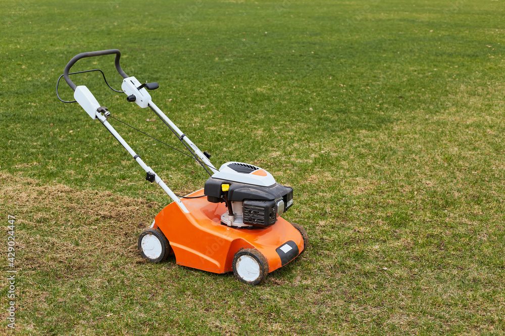 Lawn mover on green grass on background of field or garden. Machine for cutting lawns. Grass-cutter outdoors, special equipment for taking care of sward.