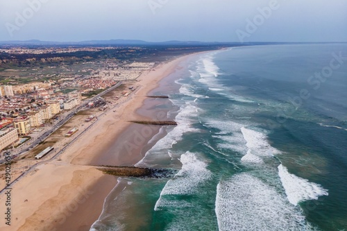 Aerial view of Costa da Caparica landscape at sunset, view of the majestic beach with rough Atlantic Ocean rolling on the shoreline, Setubal, Portugal.