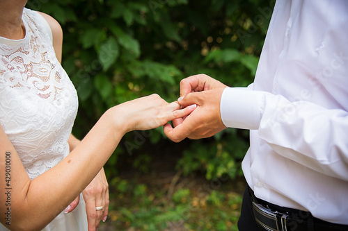 groom's hand putting a wedding ring on bride's finger