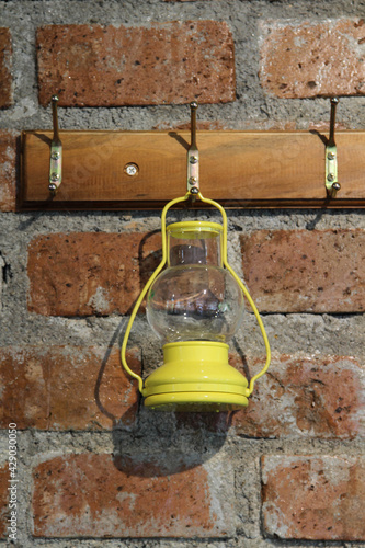 Yellow oil lamp hanging on brick wall.