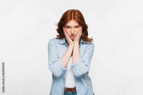 displeased redhead woman in blue plaid shirt puffing cheeks isolated on white.