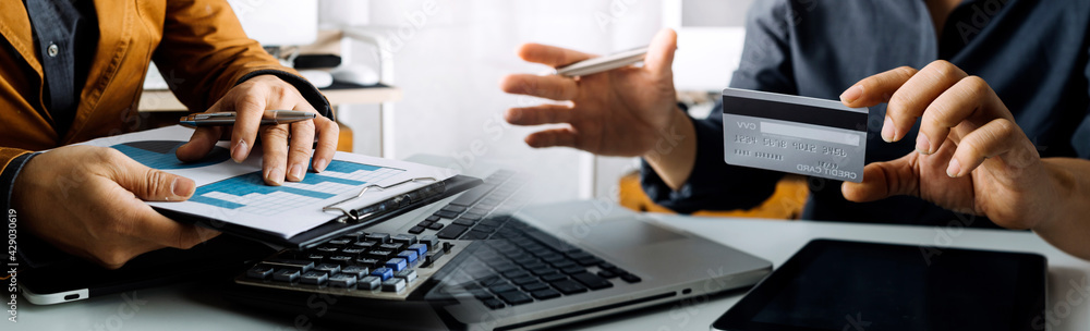 Business people use tablets and hold credit cards as an online shopping concept With a calculator and a book placed on the table Business people use tablets and hold credit cards as an online shopping concept With a calculator and a book placed on the table