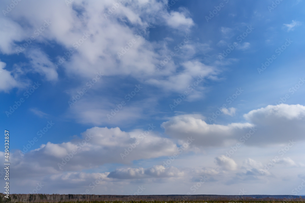 The sky is deep blue with many floating cumulus clouds. View of a beautiful sky with white clouds without any objects. The texture of the blue and white sky. Serene sky on a sunny day