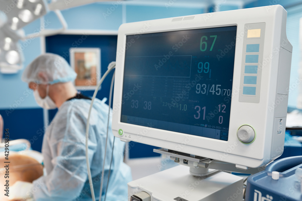 Anesthesiologist keeping track of vital functions of the body during cardiac surgery. Surgeon looking at medical monitor during surgery. Doctor checking monitor for patient health status. Anesthesiologist keeping track of vital functions of the body during cardiac surgery. Surgeon looking at medical monitor during surgery. Doctor checking monitor for patient health status.