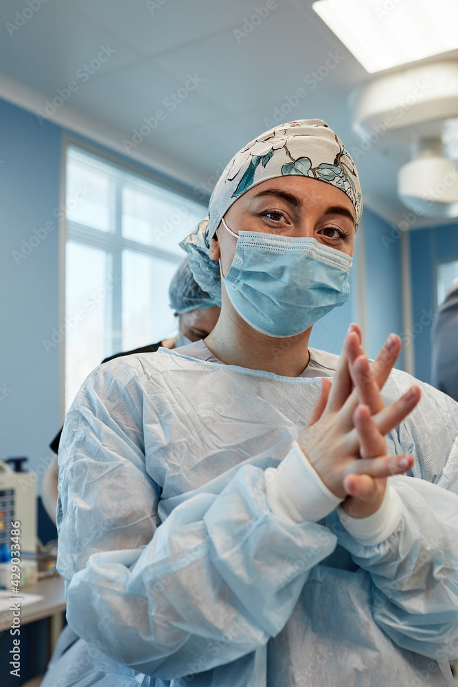 A team of surgeons is preparing for surgery. Surgeons wear sterile clothing before surgery with the help of nurses, sterile gowns, gloves, masks, in the intensive care unit.