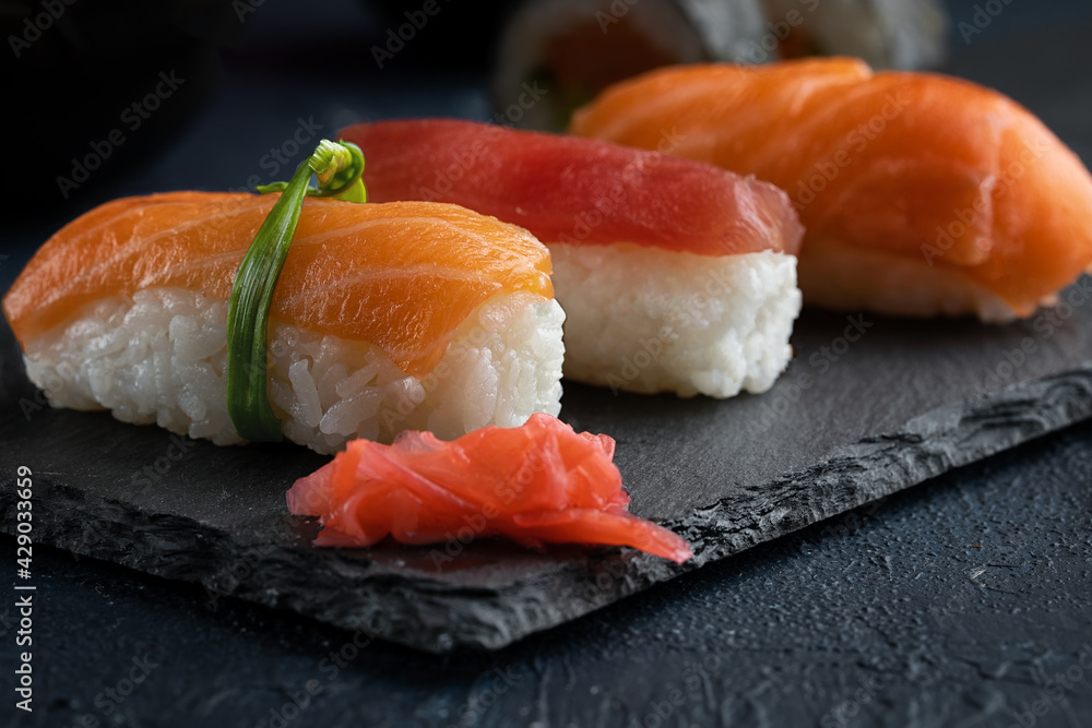 Rainbow Sushi nigiri with salmon, tuna and vegetables placed on black rock.Japan restaurant menu.Close up. Rainbow Sushi nigiri with salmon, tuna and vegetables placed on black rock.Japan restaurant menu.Close up.