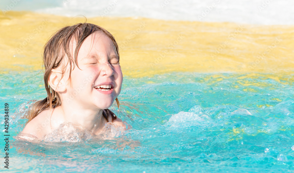 Happy child with closed eyes in the swimming pool for children.
