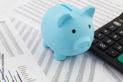 Piggy bank and calculator on financial documents. Investment, tax and savings concept.