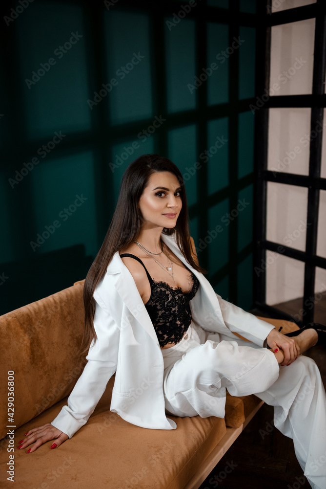 Fototapeta premium Fashion portrait of pretty sexy young brunette woman in white pantsuit