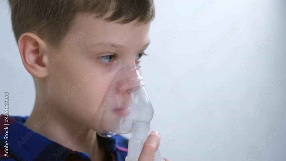 Portrait of child teen boy is breathing in mask using nebulizer for inhalation procedure at home. Fibrosis, covid-19, asthma, copd. Treatment, cure and procedure. Using inhaler for therapy. Portrait of child teen boy is breathing in mask using nebulizer for inhalation procedure at home. Fibrosis, covid-19, asthma, copd. Treatment, cure and procedure. Using inhaler for therapy.