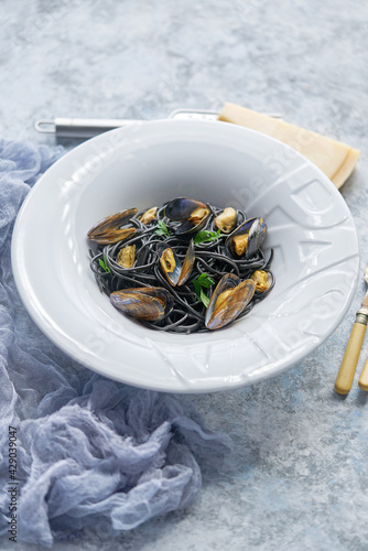 Black seafood spaghetti pasta with mussels over stone background. Mediterranean delicious food