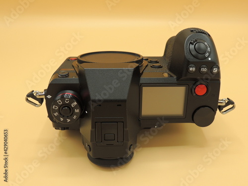 A black medium-format camera with a CMOS sensor. Yellow background. Macro photography.