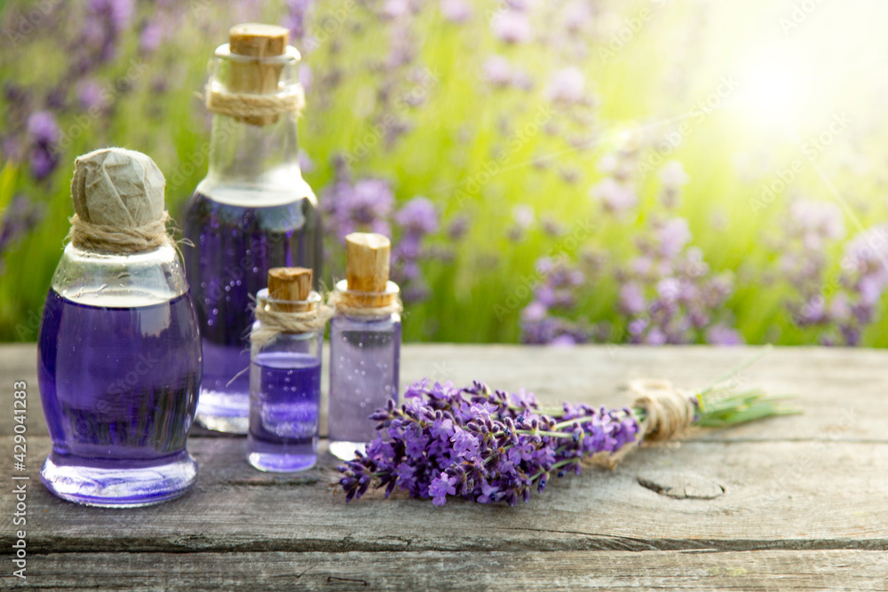 Lavender Essential oil bottle on wood table and flowers field Lavender Essential oil bottle on wood table and flowers field