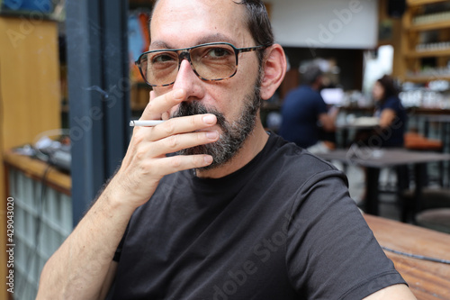 Close up portrait of a matured man who is smoking cigarette in a bar.