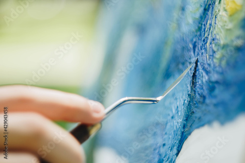 the hand of a European artist holds a mastekhin smeared in oil paint and draws a picture. Van Gogh's replica Starry night. blurred background. Close-up