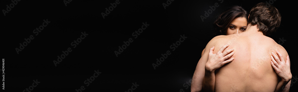 back view of shirtless man hugging woman isolated on black, banner. back view of shirtless man hugging woman isolated on black, banner.