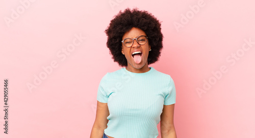 afro black woman with cheerful, carefree, rebellious attitude, joking and sticking tongue out, having fun