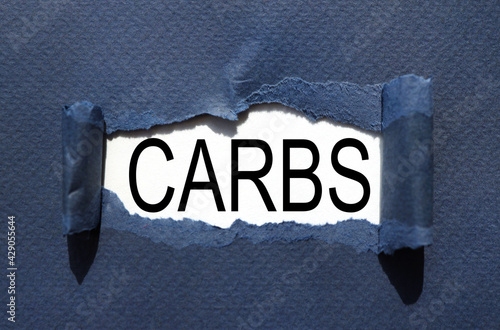 carbs. text inside torn blue paper. white sheet with black font.