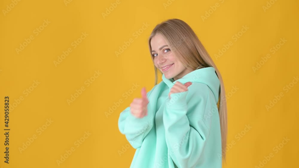 Positive young girl posing isolated on yellow studio background. Woman Looking approvingly at camera showing thumbs up, like sign positive something good. People lifestyle concept. Positive young girl posing isolated on yellow studio background. Woman Looking approvingly at camera showing thumbs up, like sign positive something good. People lifestyle concept.