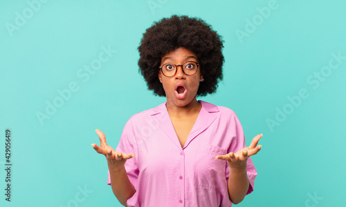 afro black woman feeling extremely shocked and surprised, anxious and panicking, with a stressed and horrified look photo