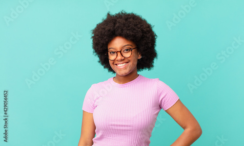afro black woman smiling happily with a hand on hip and confident, positive, proud and friendly attitude