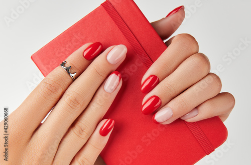 Womans hand holding notepad over white background. Manicure design trends