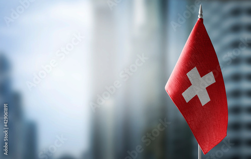 A small flag of Switzerland on the background of a blurred background