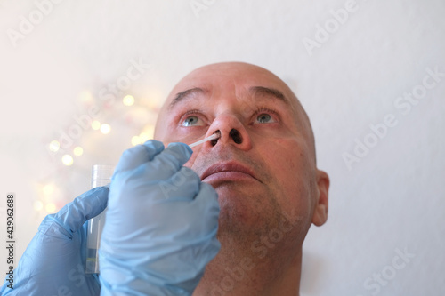 Obraz na plátne face of an elderly bald man close-up, laboratory assistant, doctor takes swab sa