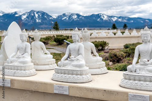 Statues of Buddha sitting side by side with the snow covered mountains of Montana in the distance. photo