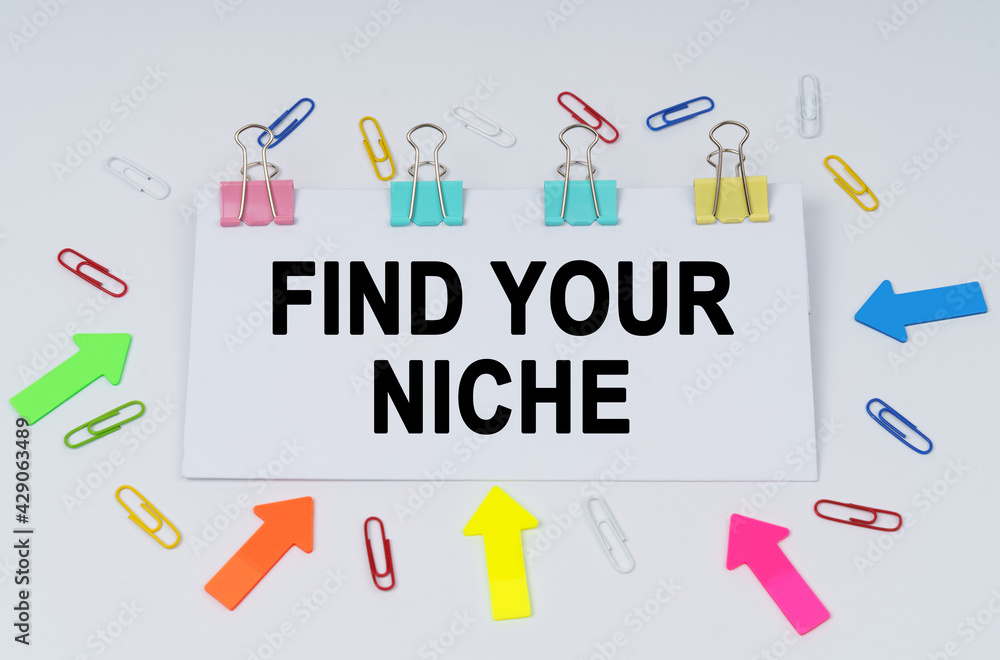 On the table there are paper clips and directional arrows, a sign that says - Find Your Niche