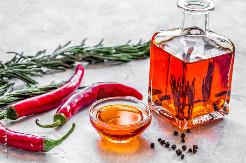 Foto Bottle with chili oil and herbs on stone background