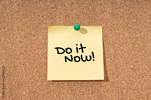 Do it now message on yellow note on cork board
