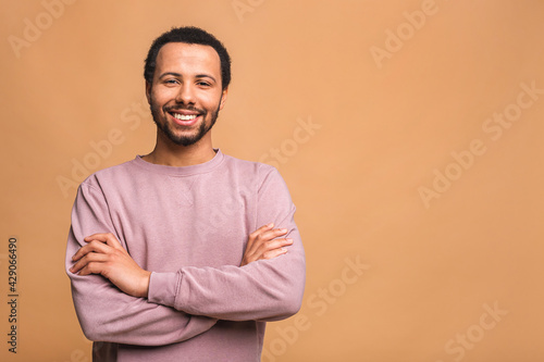 A young happy smiling funny black African American male isolated against beige background.