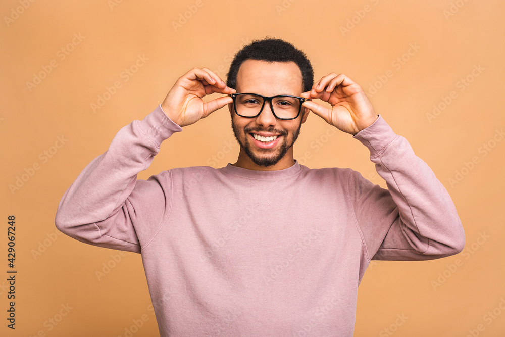 A young happy smiling funny black African American male isolated against beige background. A young happy smiling funny black African American male isolated against beige background.