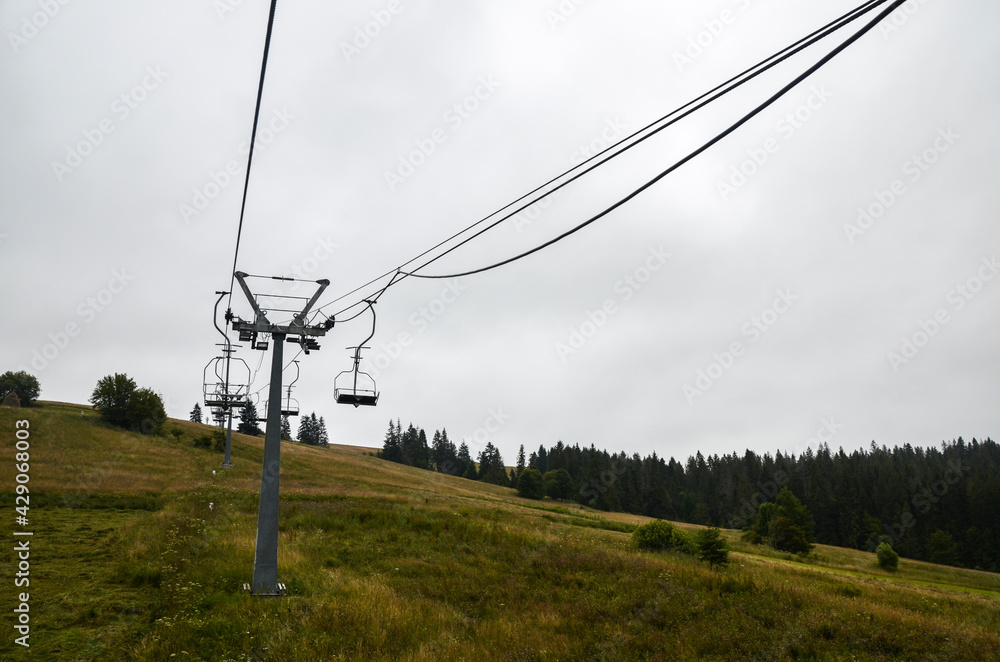Summer cloudy landscape with empty ski lift on the green grassy hill in the Carpathian mountains, Ukraine
