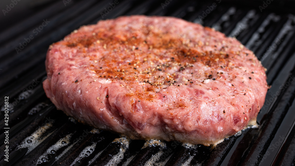 Hamburger patty getting cooked in a cast iron grill pan. The different seasonings is clearly visible on top of the patty.
Hamburger meat and food preparation concept. Hamburger patty getting cooked in a cast iron grill pan. The different seasonings is clearly visible on top of the patty.
Hamburger meat and food preparation concept.