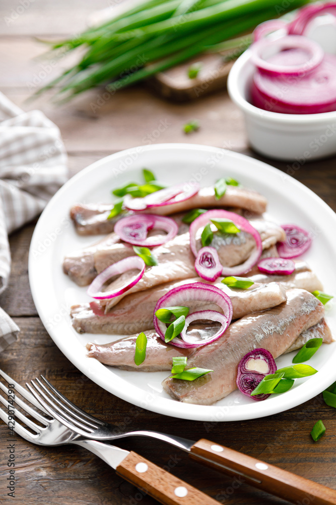 Pickled herring fillet with onion on plate Pickled herring fillet with onion on plate