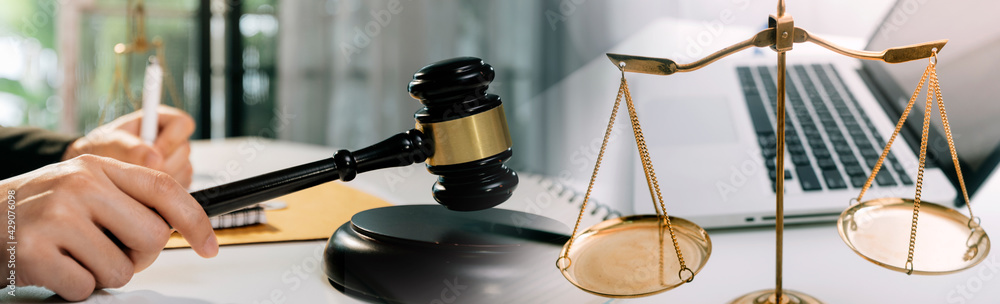 Justice and law concept.Male judge in a courtroom with the gavel, working with, computer and docking keyboard, eyeglasses, on table in morning light