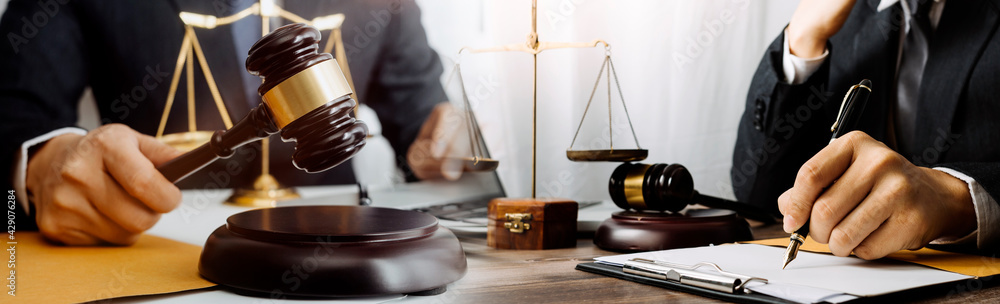 Business and lawyers discussing contract papers with brass scale on desk in office. Law, legal services, advice, justice and law concept picture with film grain effect Business and lawyers discussing contract papers with brass scale on desk in office. Law, legal services, advice, justice and law concept picture with film grain effect
