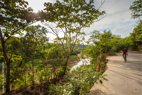 Women bicyclist riding along a washed-out road in Colombia. photo