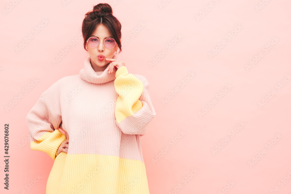Young beautiful smiling female in trendy summer colorful sweater. Sexy carefree woman posing near pink wall in studio. Positive model having fun indoors. Pretty and cheerful.Makes duck face Young beautiful smiling female in trendy summer colorful sweater. Sexy carefree woman posing near pink wall in studio. Positive model having fun indoors. Pretty and cheerful.Makes duck face