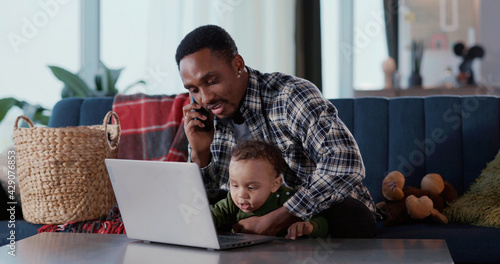 African american bonding family of cheerful father teaching upbringing his little child learning technologu using laptop at home living room. photo