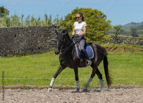 Happy woman riding black Lusitano horse, beautiful mare, outdoors.